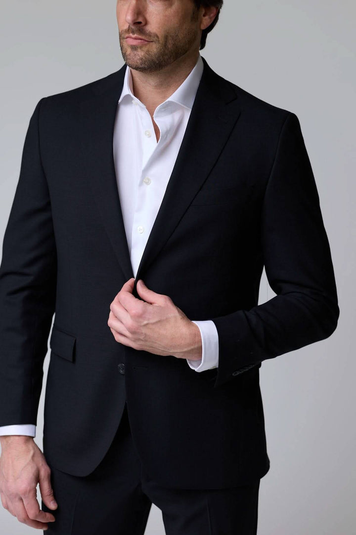 Homme en complet classique deux pièces noir, élégance intemporelle, veste à deux boutons, idéal pour occasions formelles.