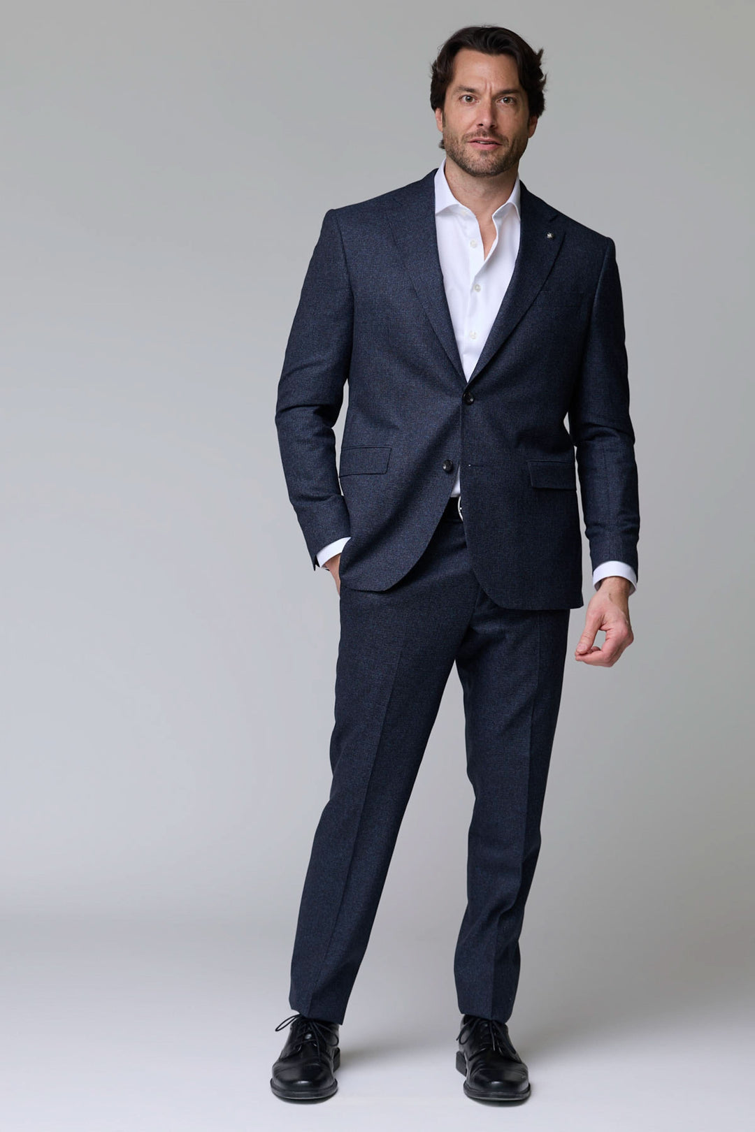 Homme portant un complet en laine texturée avec veste à deux boutons et pantalon ajusté, parfait pour des occasions élégantes.