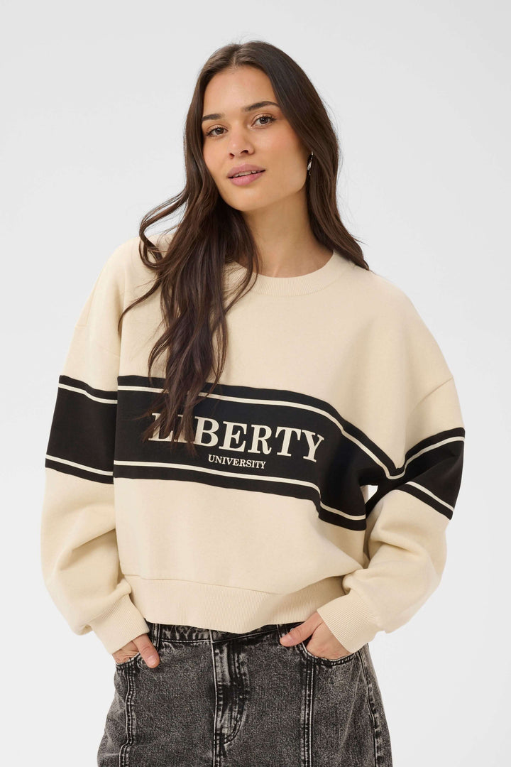 Femme portant un Coton ouaté Assia décontracté avec motif graphique universitaire, coupe ample et manches longues.