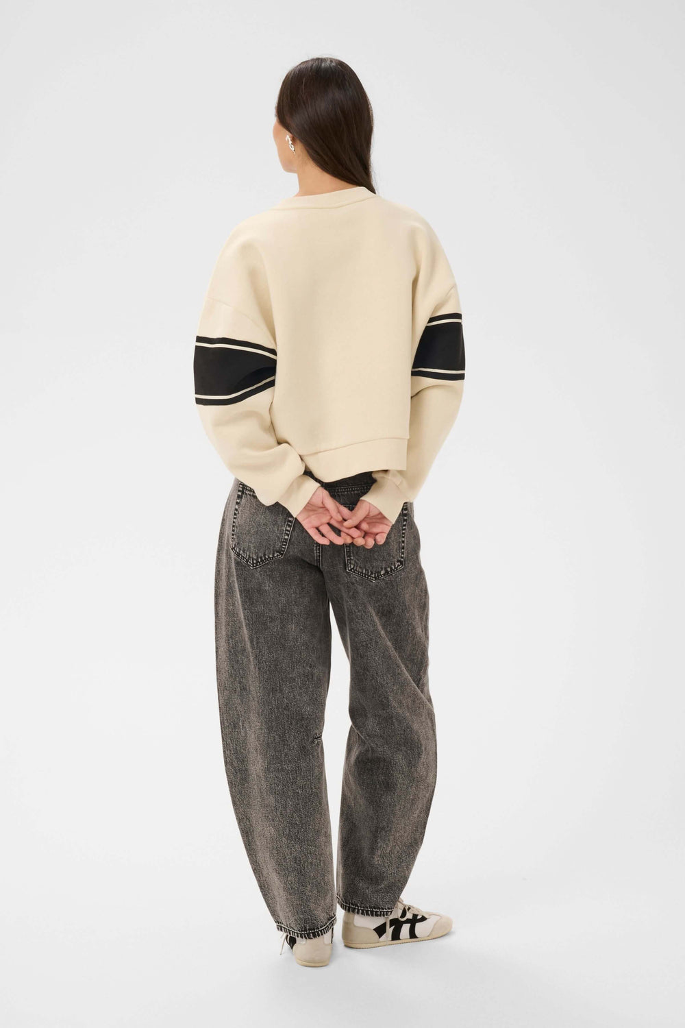 Person wearing Coton ouaté Assia, contemporary relaxed sweater with graphic design, paired with casual jeans and sneakers.