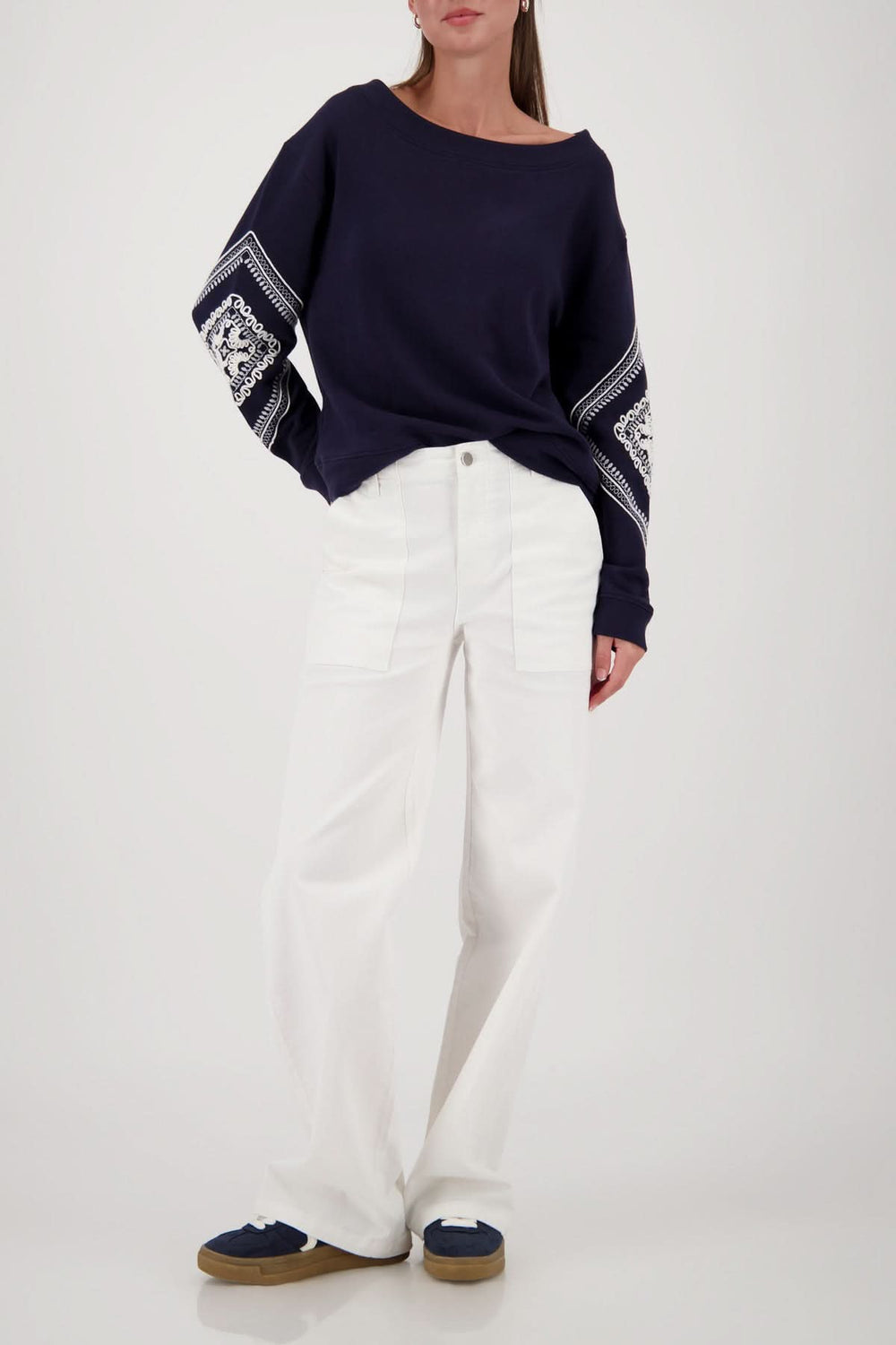 Femme portant un coton ouaté avec broderies décoratives et manches longues, associé à un pantalon blanc ample.