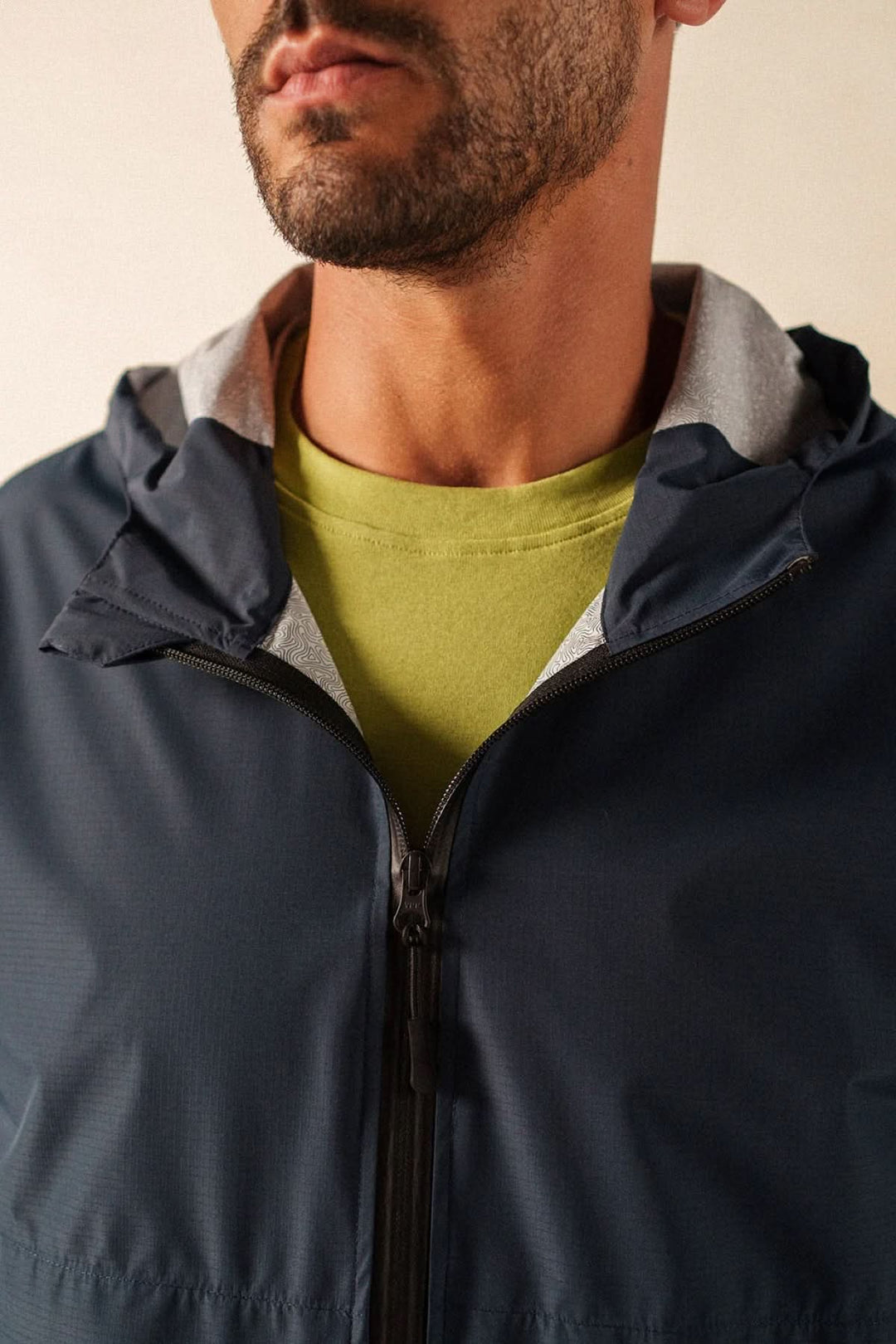 Homme portant un coupe-vent léger à fermeture zippée, style sportif moderne.