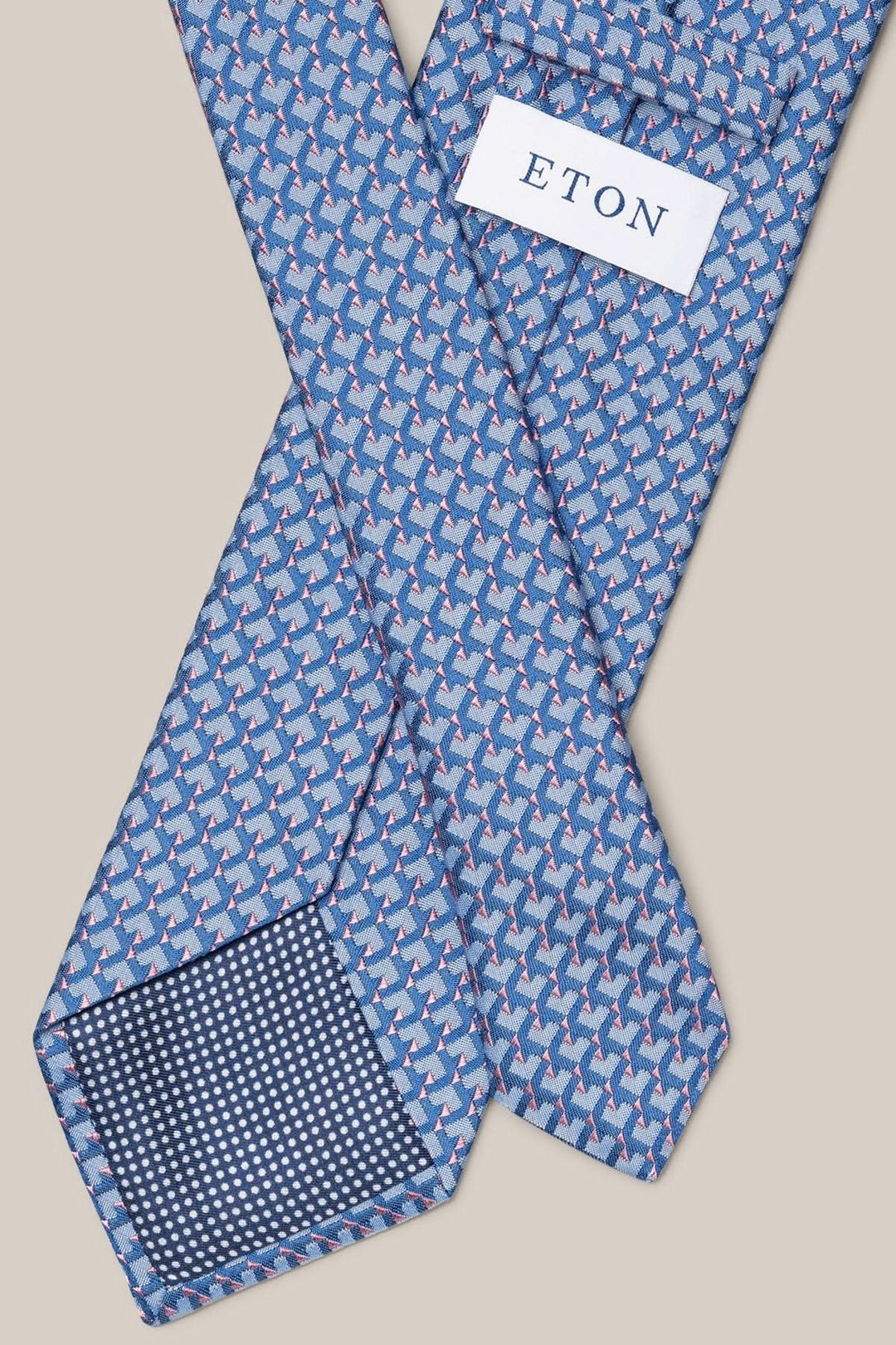 Cravate en soie Eton avec motif géométrique bleu, gris et rose pâle, ajoutant élégance moderne à un costume.