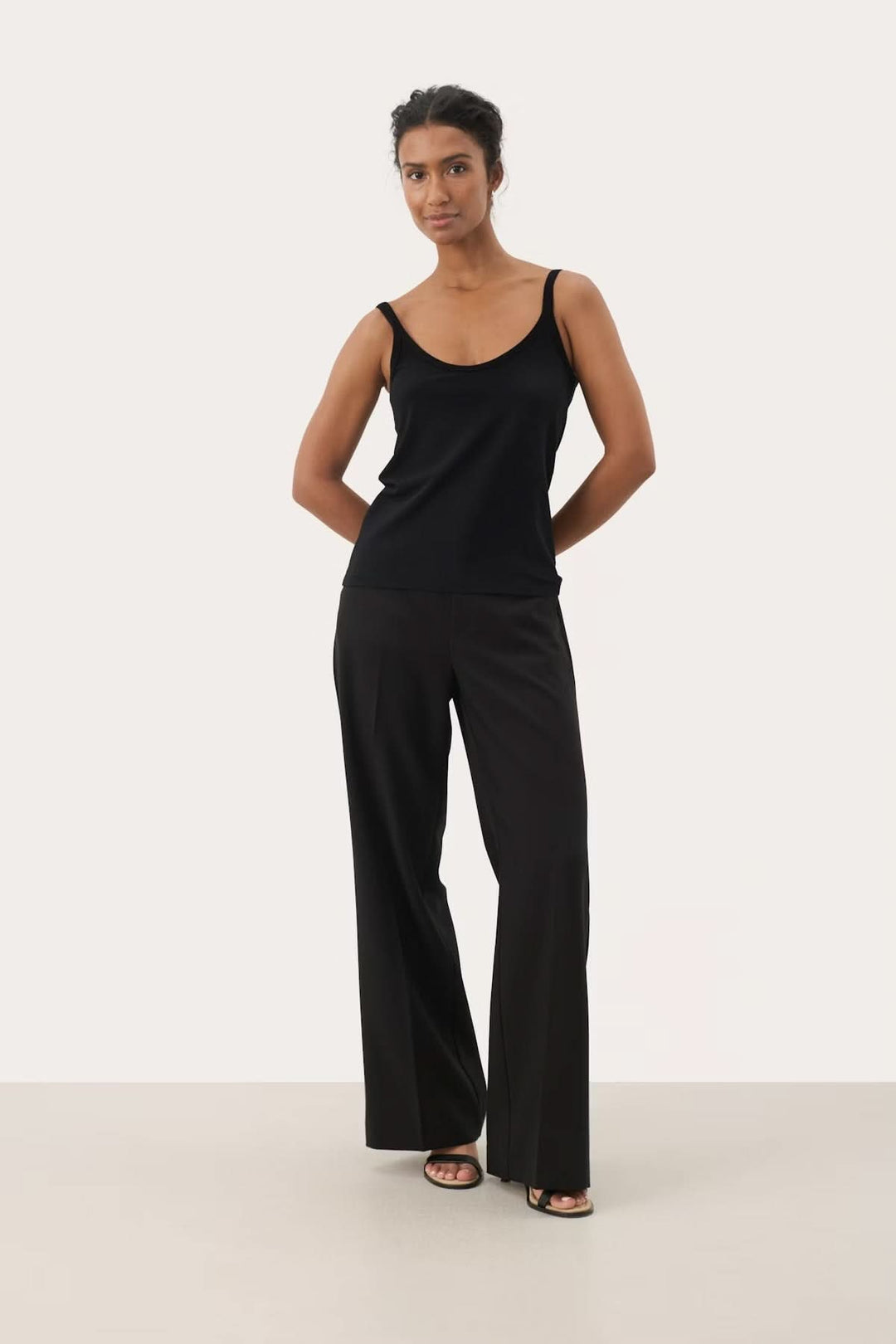 Femme portant un débardeur encolure arrondie avec un pantalon noir, style élégant et décontracté.