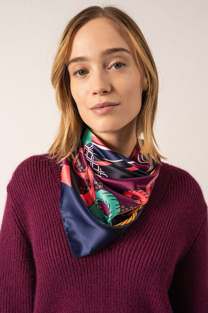 Foulard carré fond marin porté par femme avec motif nautique, couleur vive et élégante, dimensions 90x90 cm.