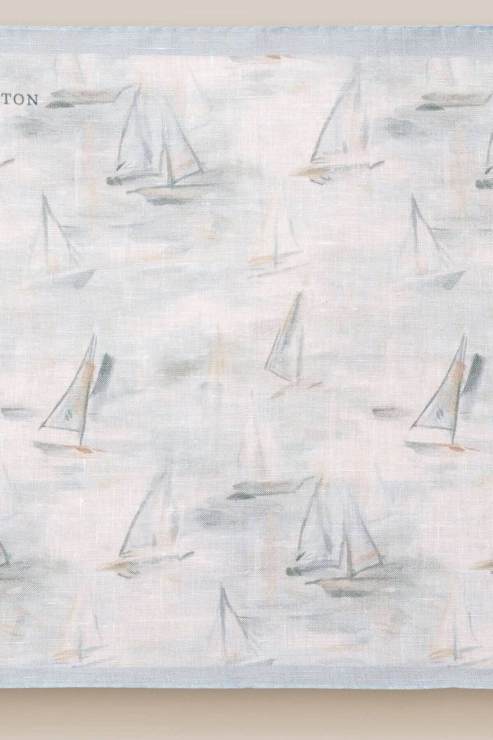 Foulard de poche en lin bleu avec motif de voiliers, idéal pour une touche nautique élégante.