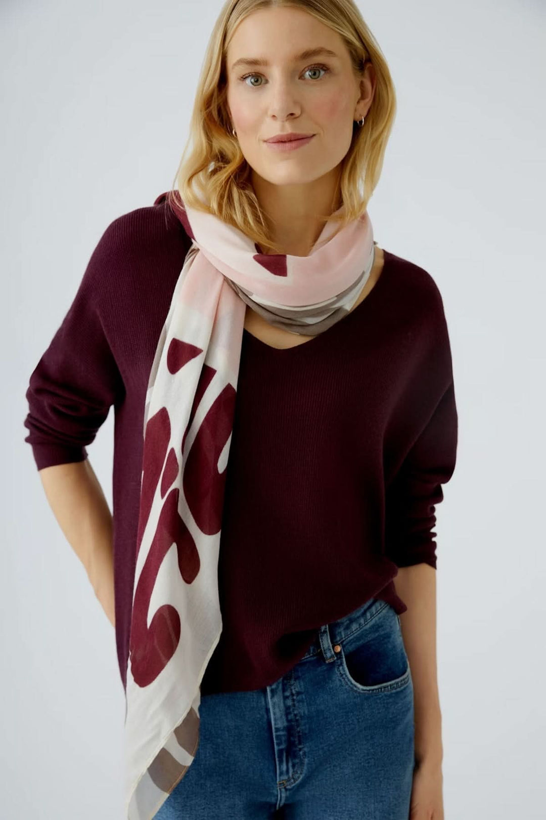 Foulard en voile léger avec imprimé artistique multicolore noué autour du cou, porté par une personne en pull bordeaux.