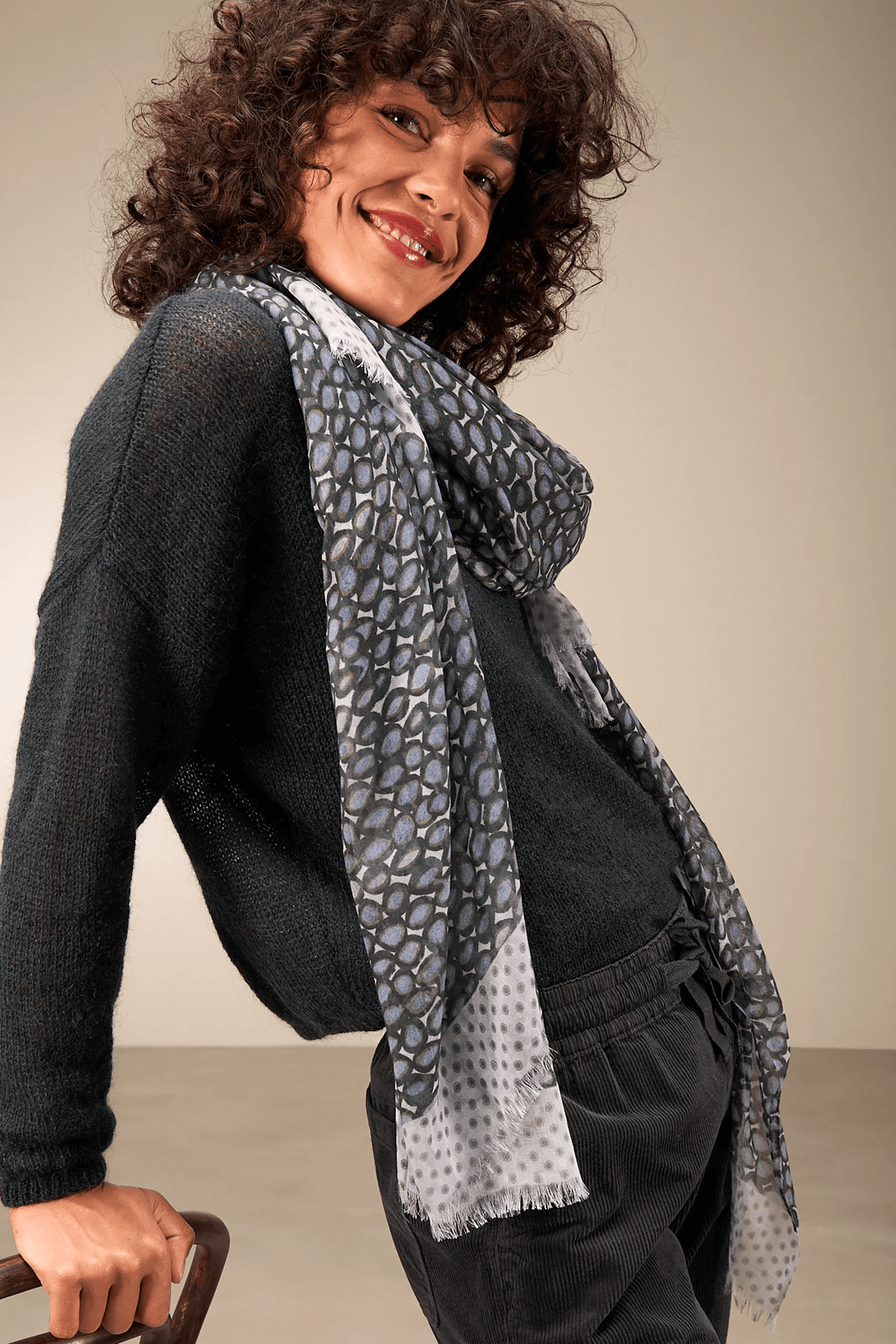 Femme portant un foulard imprimé léger et fluide, ajoutant une touche sophistiquée à son chandail d'hiver, créant un style élégant.