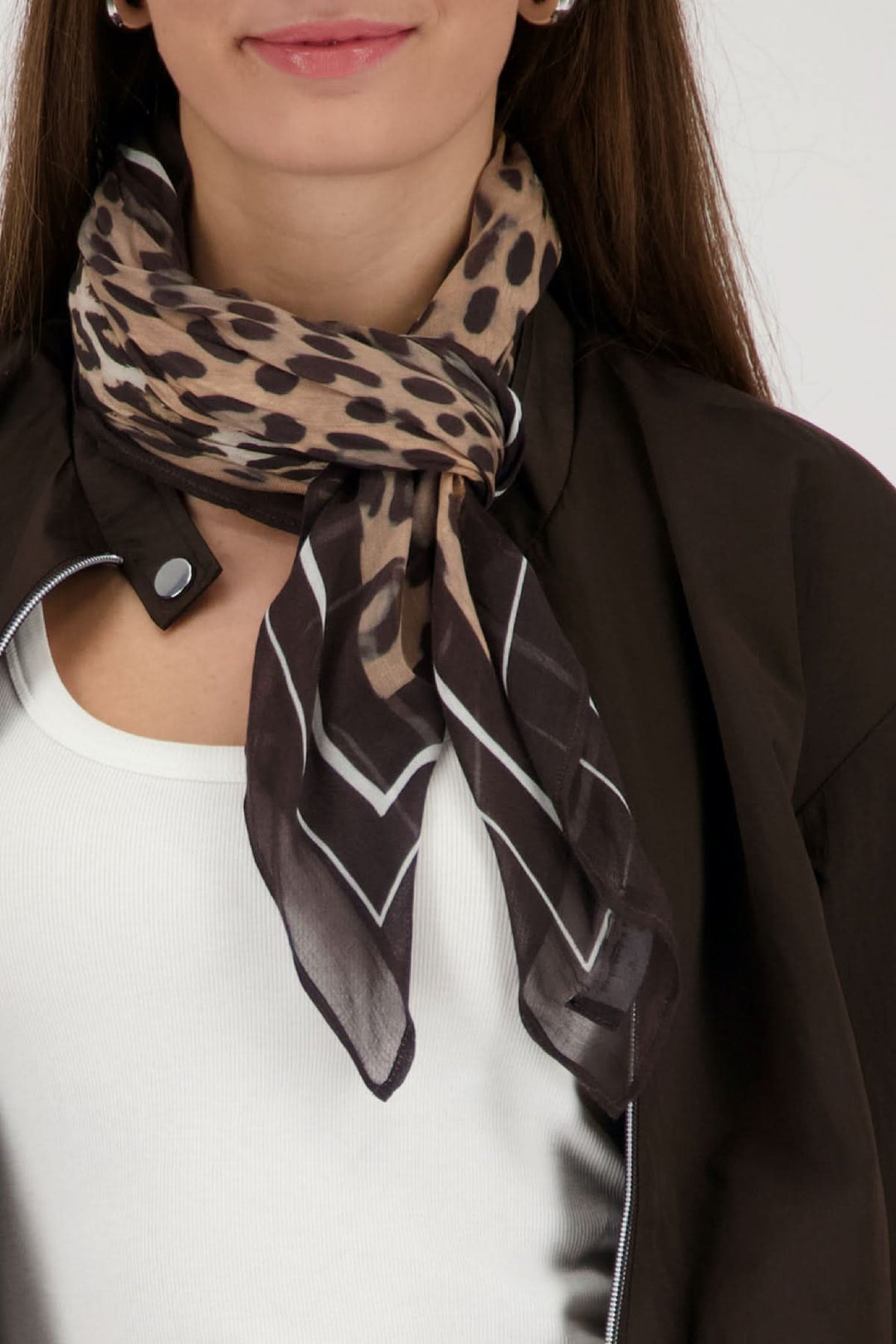 Foulard imprimé léopard artistique porté autour du cou, ajoutant une touche sophistiquée et affirmée au style. Motifs léopard élégants.