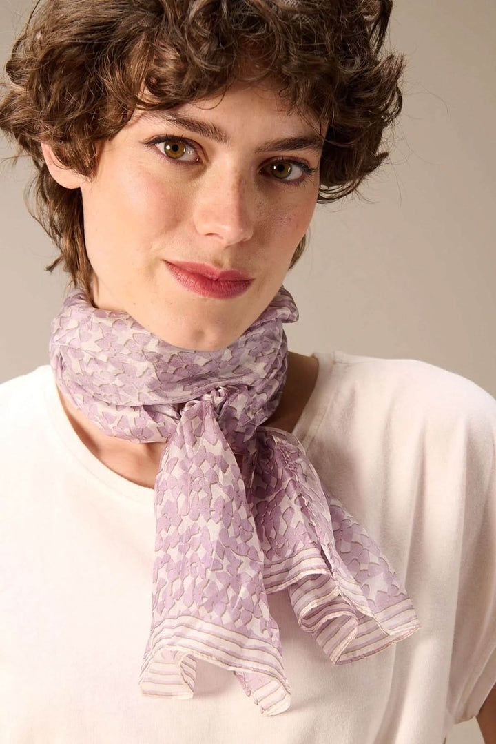 Femme portant un foulard léger imprimé autour du cou, accessoire élégant et moderne en tissu fluide et imprimé délicat.