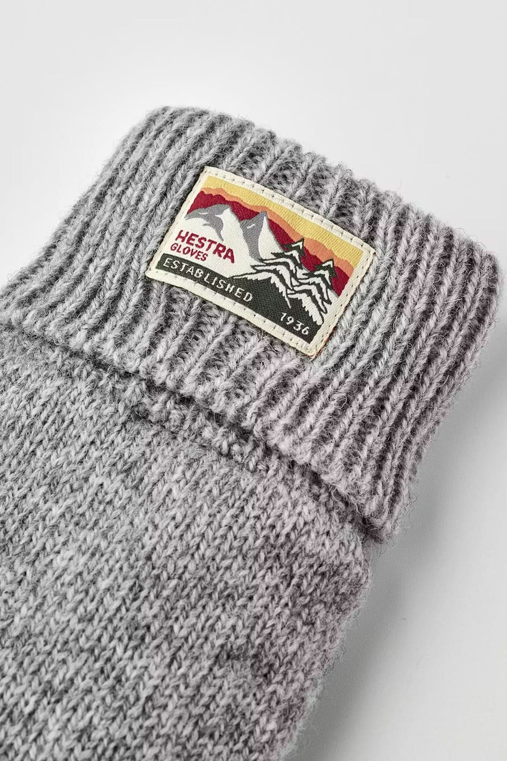 Ganst en maille gris avec poignets côtelés et étiquette de marque en tricot souple pour confort et chaleur.