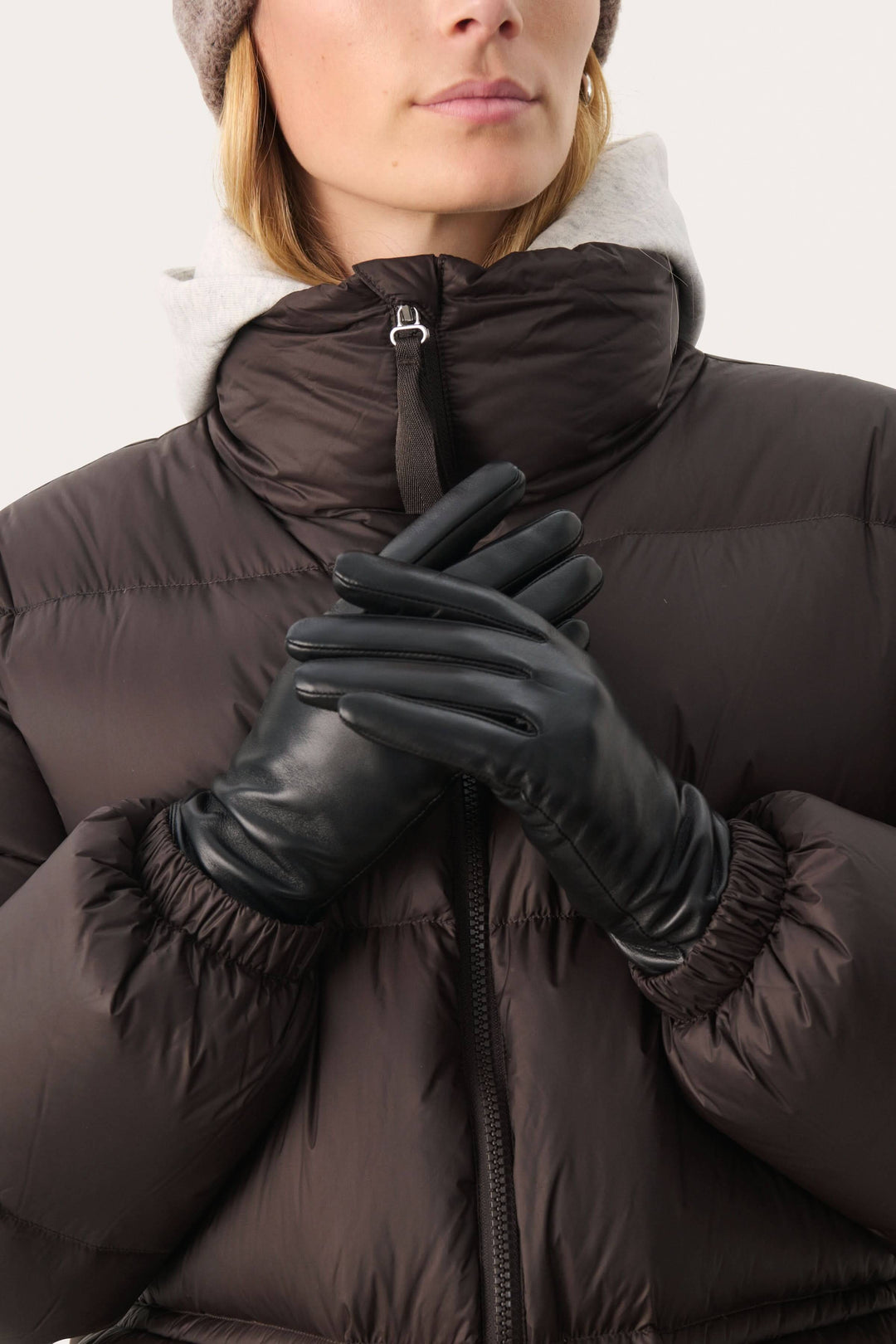 Gants en cuir véritable noir, élégants et chauds, portés avec un manteau rembourré et bonnet, style hivernal chic.