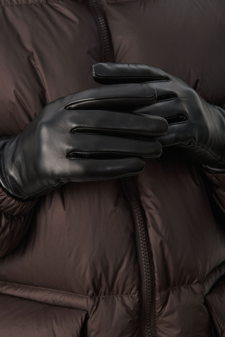Gants en cuir noir, élégants et ajustés, parés pour les journées froides, avec une doudoune brune.