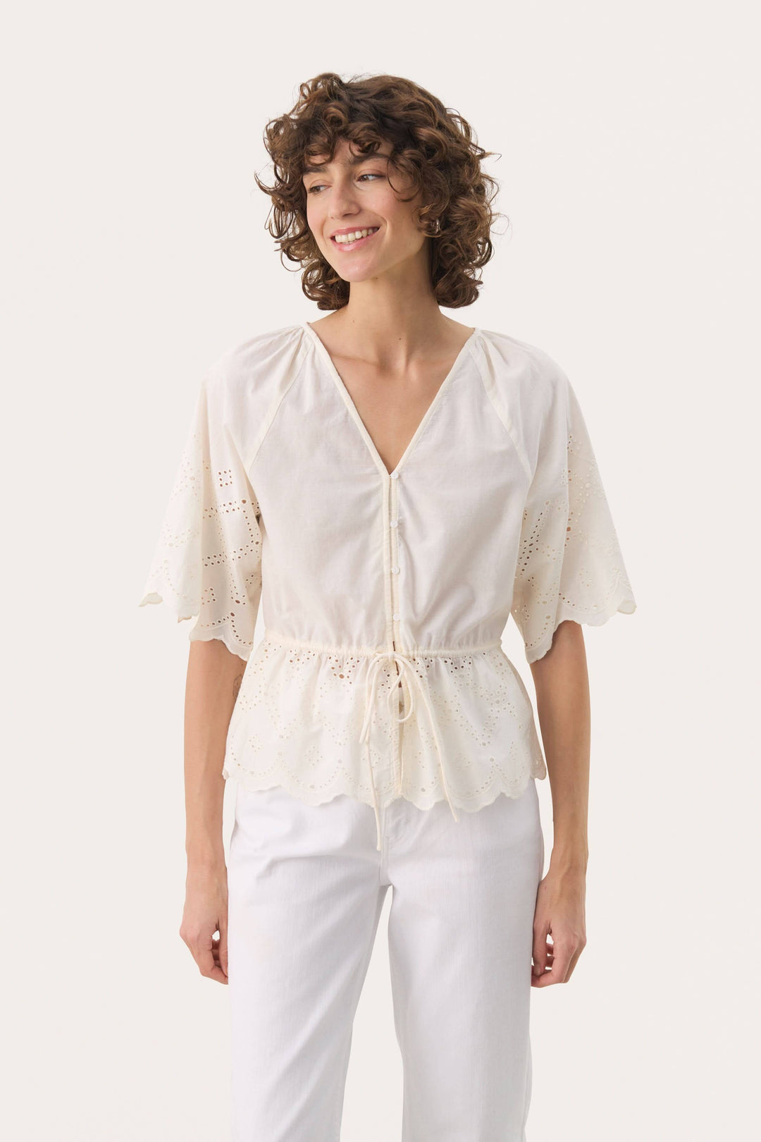 Blouse romantique en coton léger avec broderie anglaise, encolure en V et manches amples.
