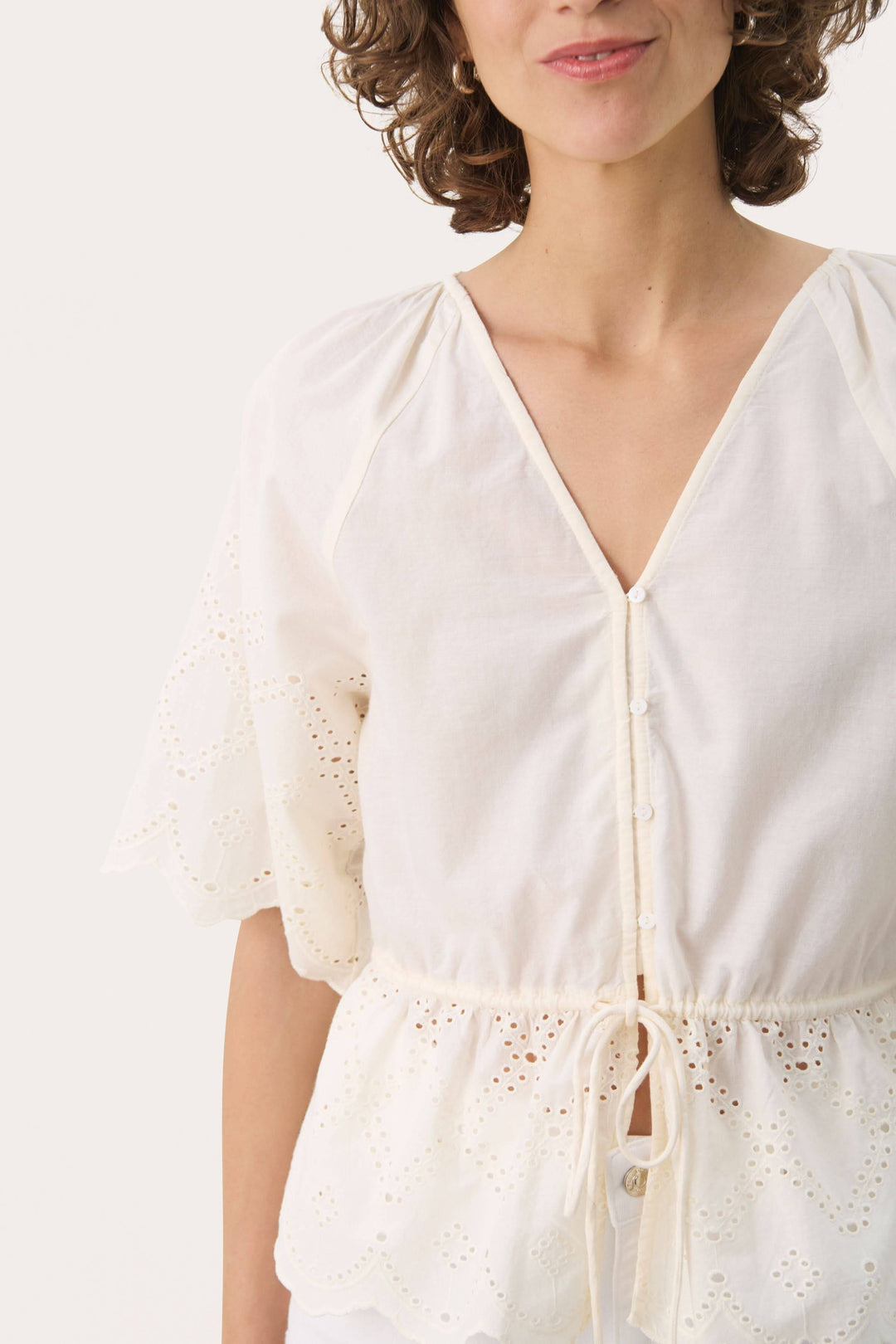Blouse romantique en coton léger avec broderie anglaise et encolure en V, parfaite pour les journées ensoleillées.