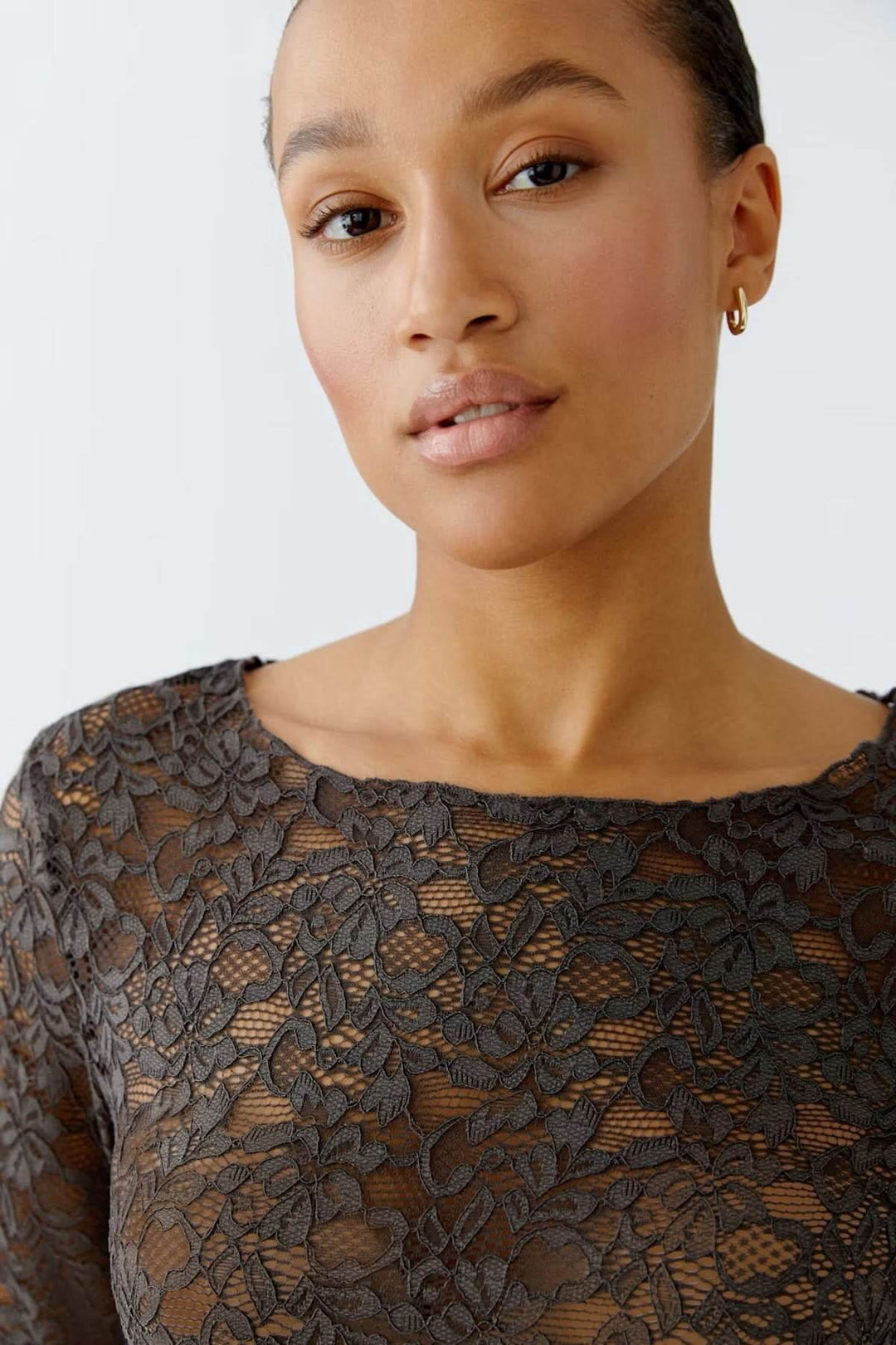 Haut en dentelle florale avec encolure bateau, coupe ajustée et manches longues pour une élégance féminine raffinée.