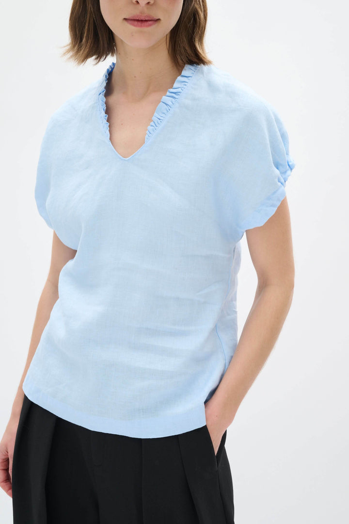 Haut en lin Rigitta bleu clair avec encolure en V et manches courtes retroussées, idéal pour l'été.