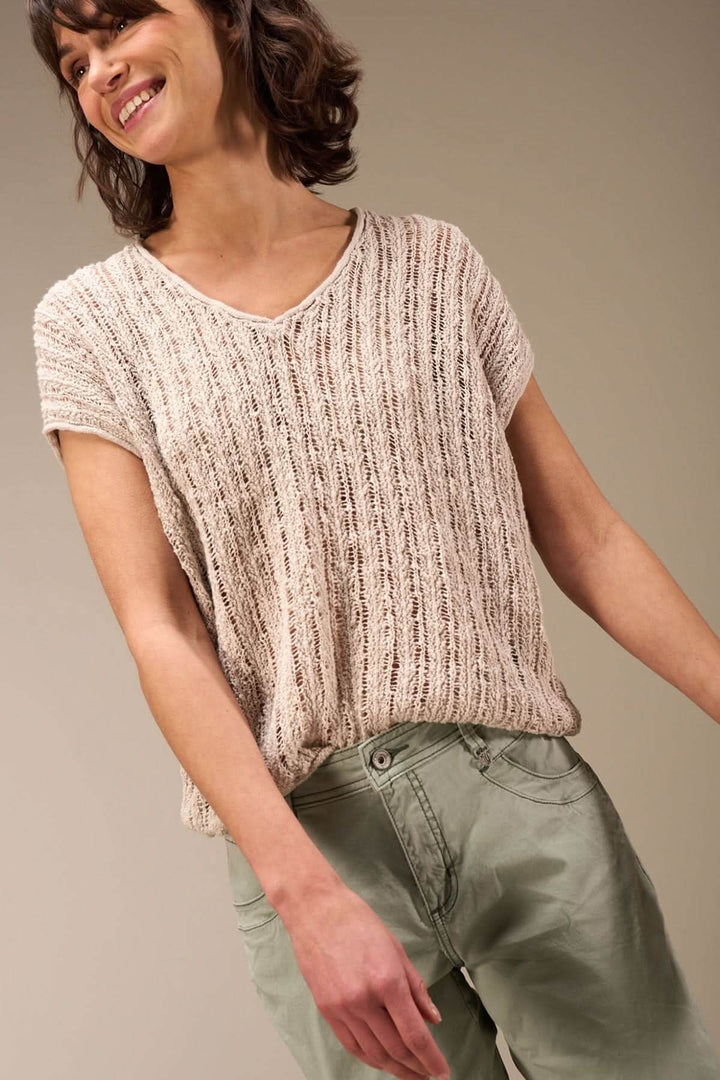 Femme souriante portant un haut en maille ajourée avec un pantalon cargo, idéal pour un look estival décontracté.