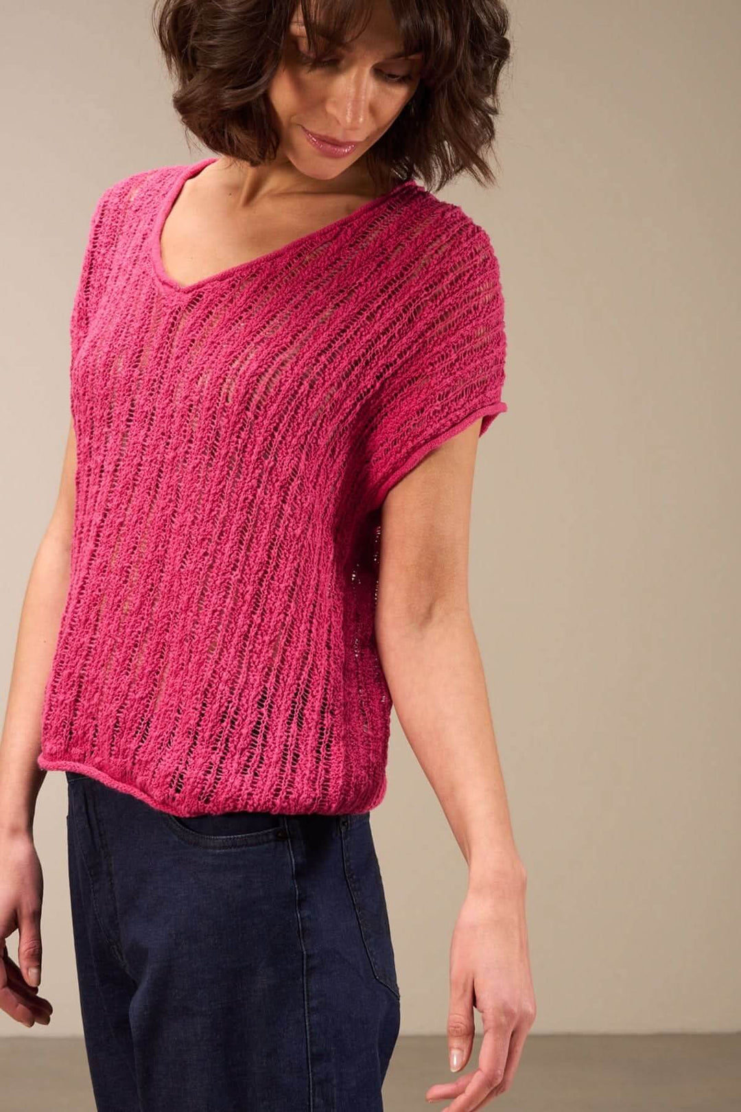 Feminine pink open-knit top with short sleeves and a flattering V-neck, perfect for sunny days and casual outfits.