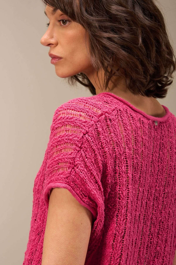 Femme portant un haut en maille ajourée rose, vue de dos, mettant en avant sa texture légère et son encolure en V.