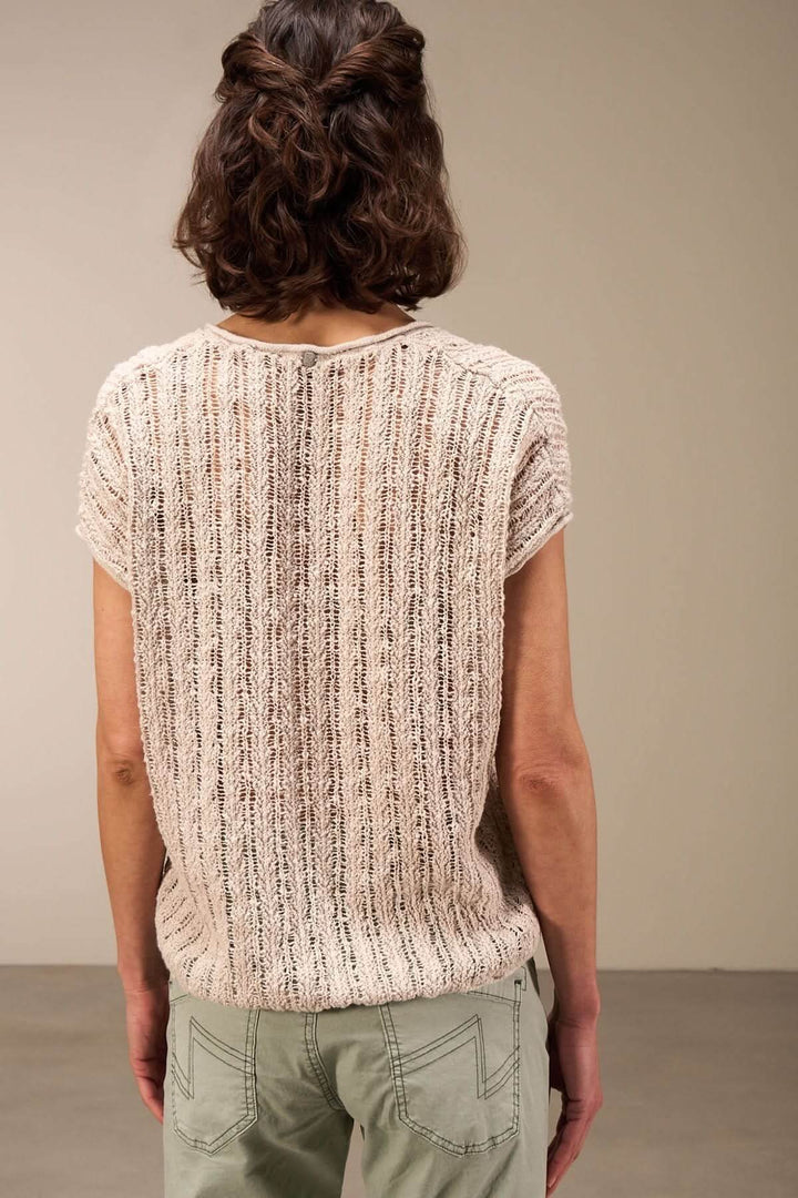 Back view of a lightweight, textured open-knit top with short sleeves, styled with cargo pants.