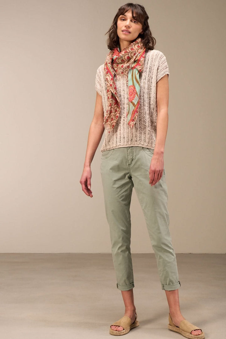 Femme portant un haut en maille ajourée, pantalon cargo léger, et écharpe colorée pour un look estivale décontracté.