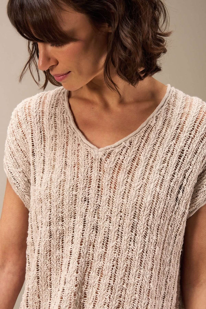 Femme portant un haut en maille ajourée avec encolure en V et coupe fluide, parfait pour un look estival.