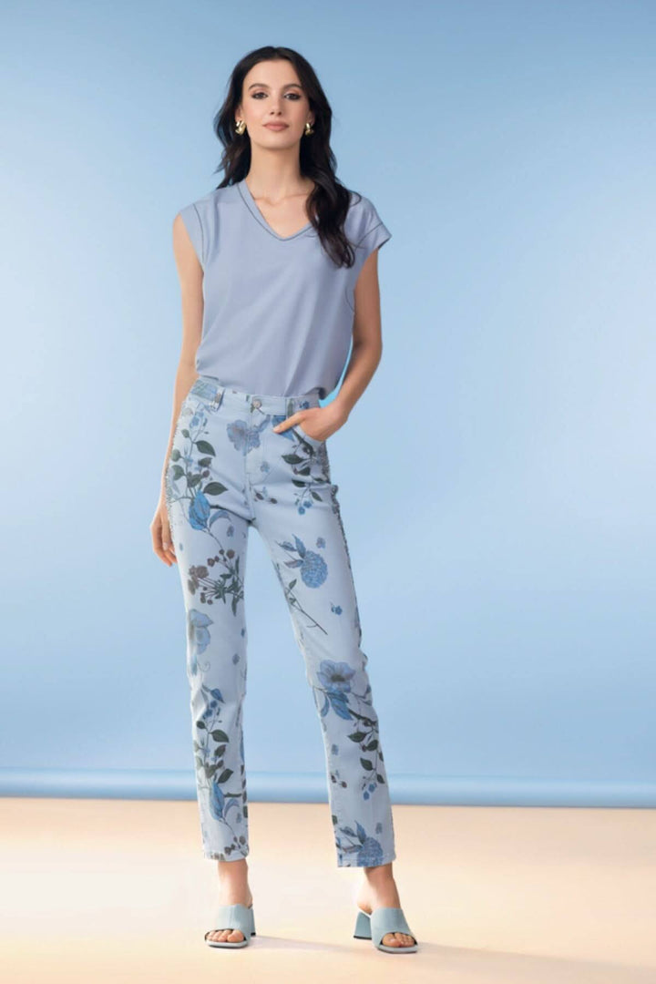 Femme portant un haut fluide col en V bleu avec un pantalon à motifs floraux, élégante et moderne.
