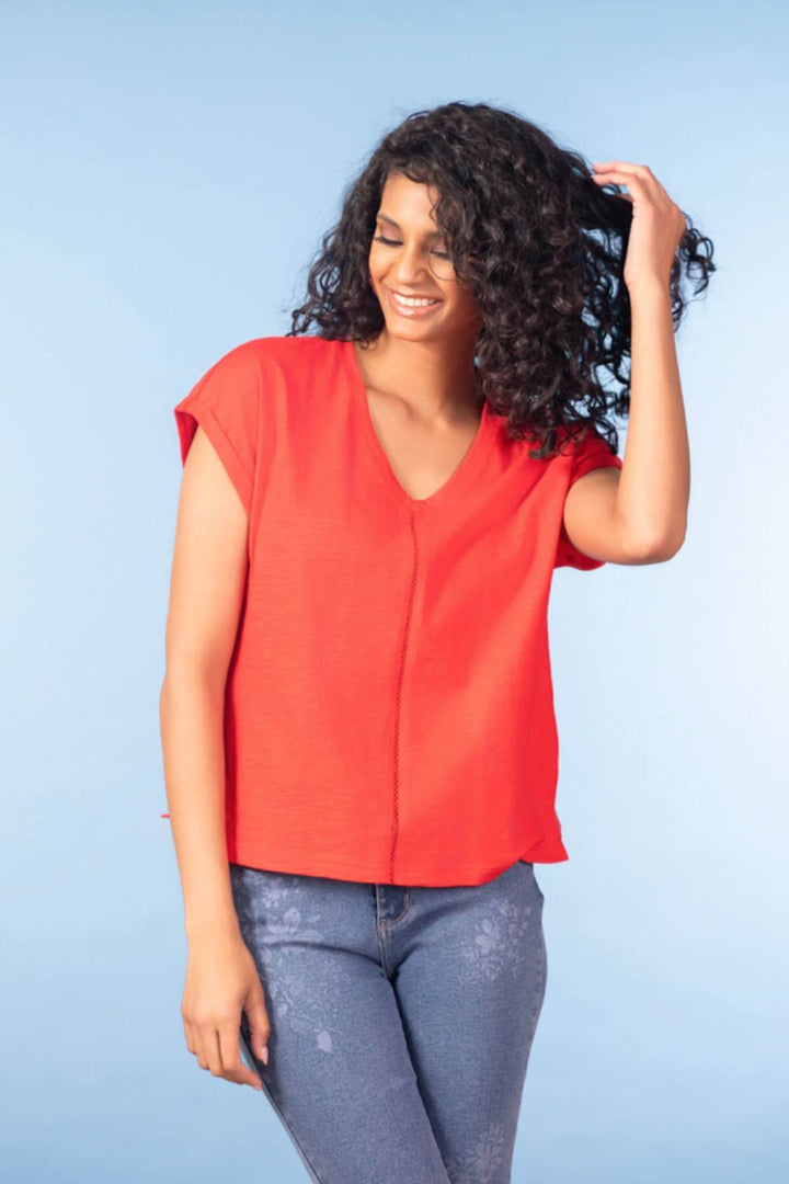 Femme portant un haut fluide col en V rouge décontracté avec manches courtes, idéal pour une tenue moderne et polyvalente.