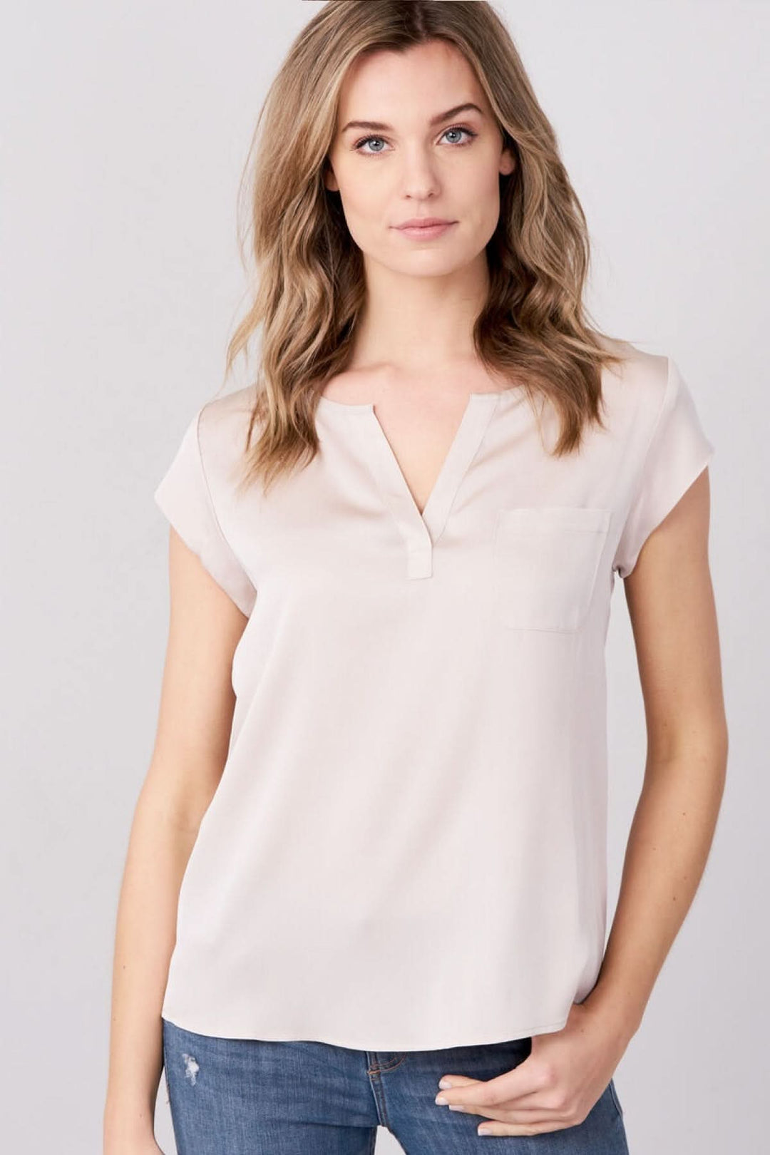 Femme portant un haut fluide col fendu manches courtes élégant et moderne, idéal pour un look polyvalent et confortable.
