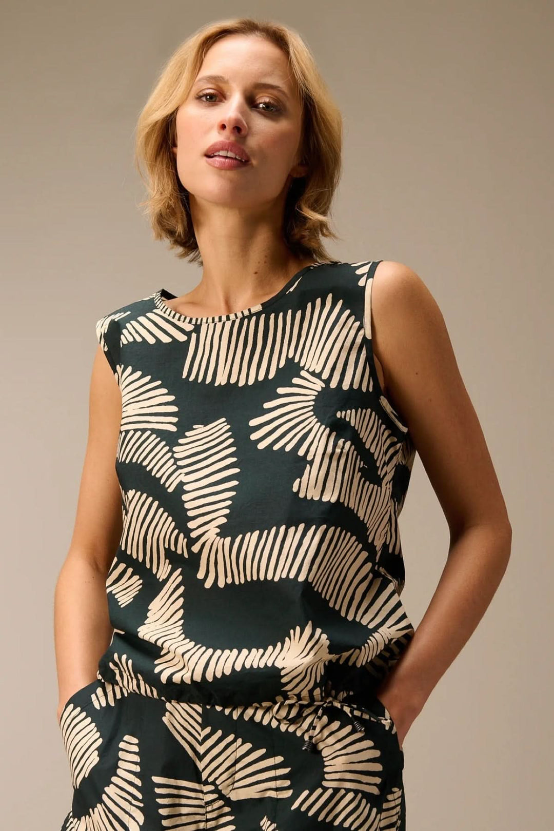 Femme portant un haut fluide sans manches imprimé avec motif audacieux, parfait pour un look contemporain et confortable.