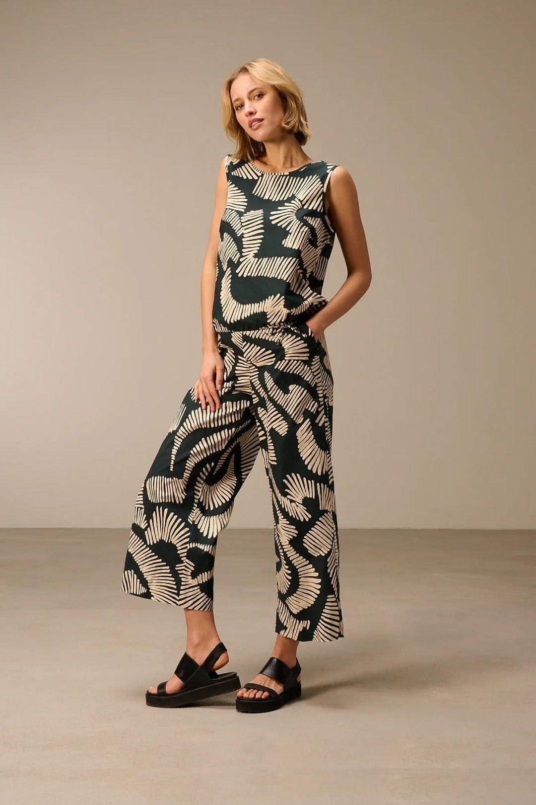 Femme portant un haut fluide sans manches imprimé, silhouette contemporaine et confortable.