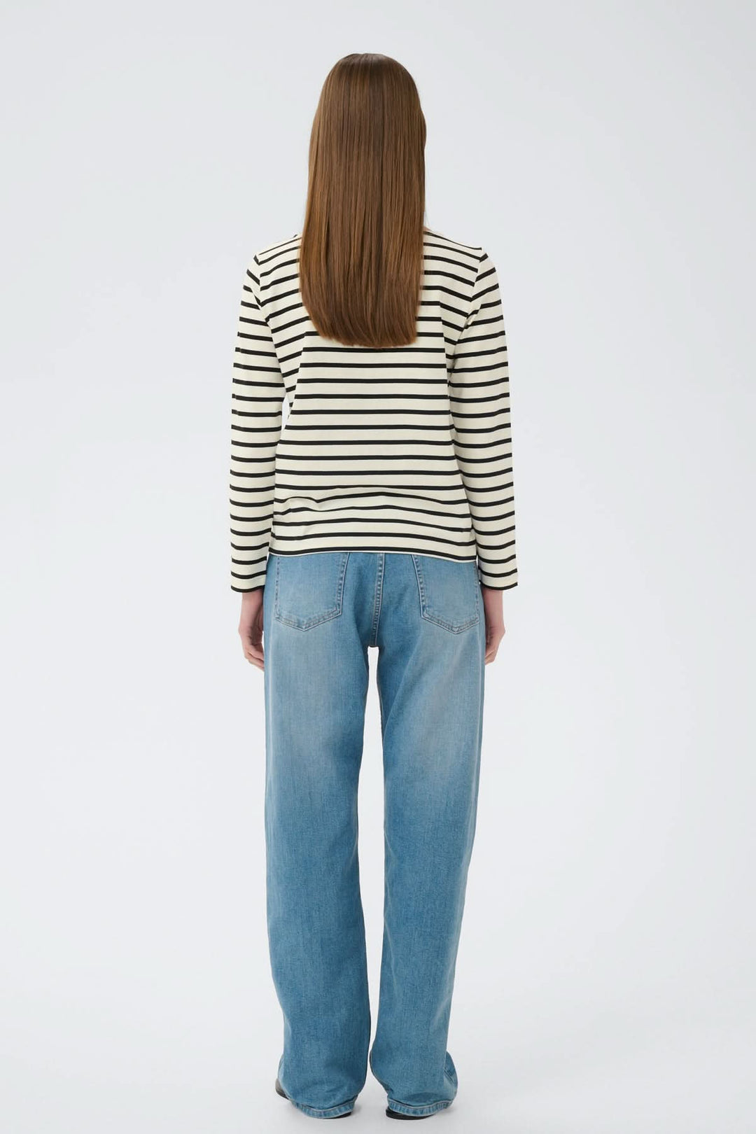 Femme portant le Haut à rayures contrastées Della, vu de dos, avec une coupe droite et des rayures modernes sur fond blanc.