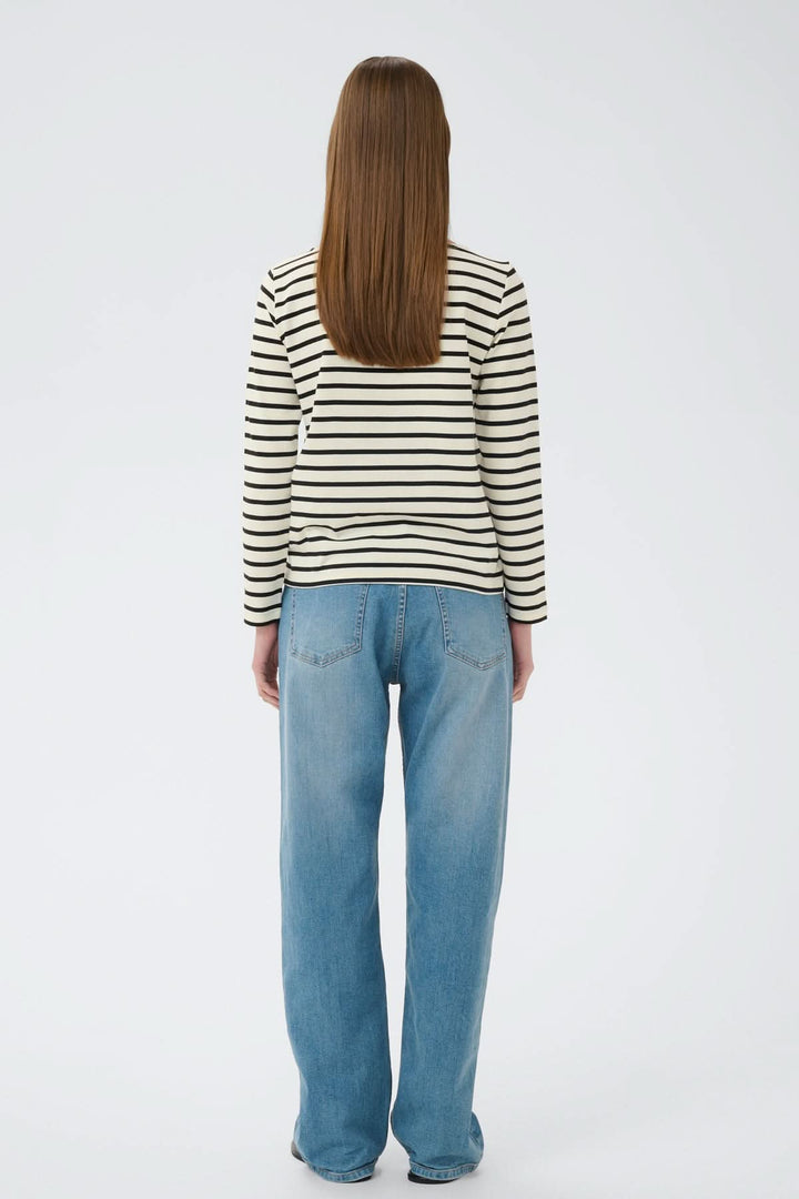 Femme portant le Haut à rayures contrastées Della, vu de dos, avec une coupe droite et des rayures modernes sur fond blanc.