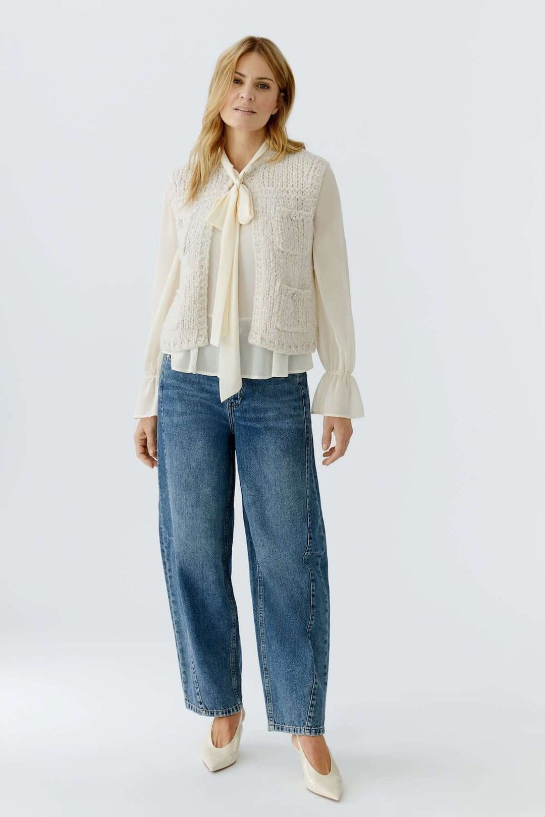 Femme portant un haut sans manches en maille, maille douce et duveteuse, avec un pantalon en jean. Look moderne et raffiné pour mi-saison.