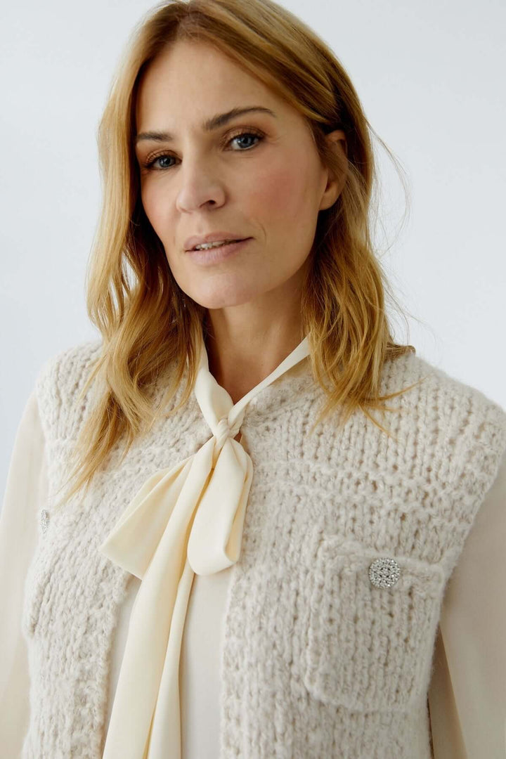 Femme portant un haut sans manches en maille avec une chemise blanche pour un look moderne et raffiné.