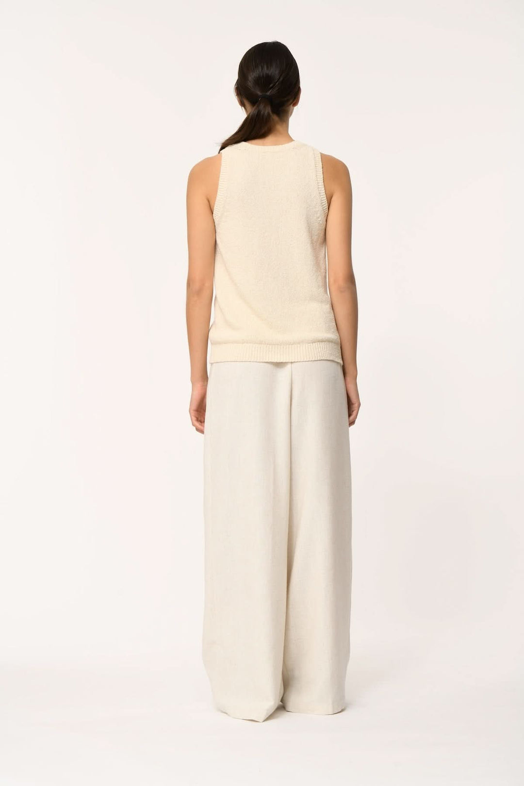 Femme portant le haut sans manches en maille texturée JANICIA, vu de dos, coupe fluide et silhouette épurée, tenue minimaliste.
