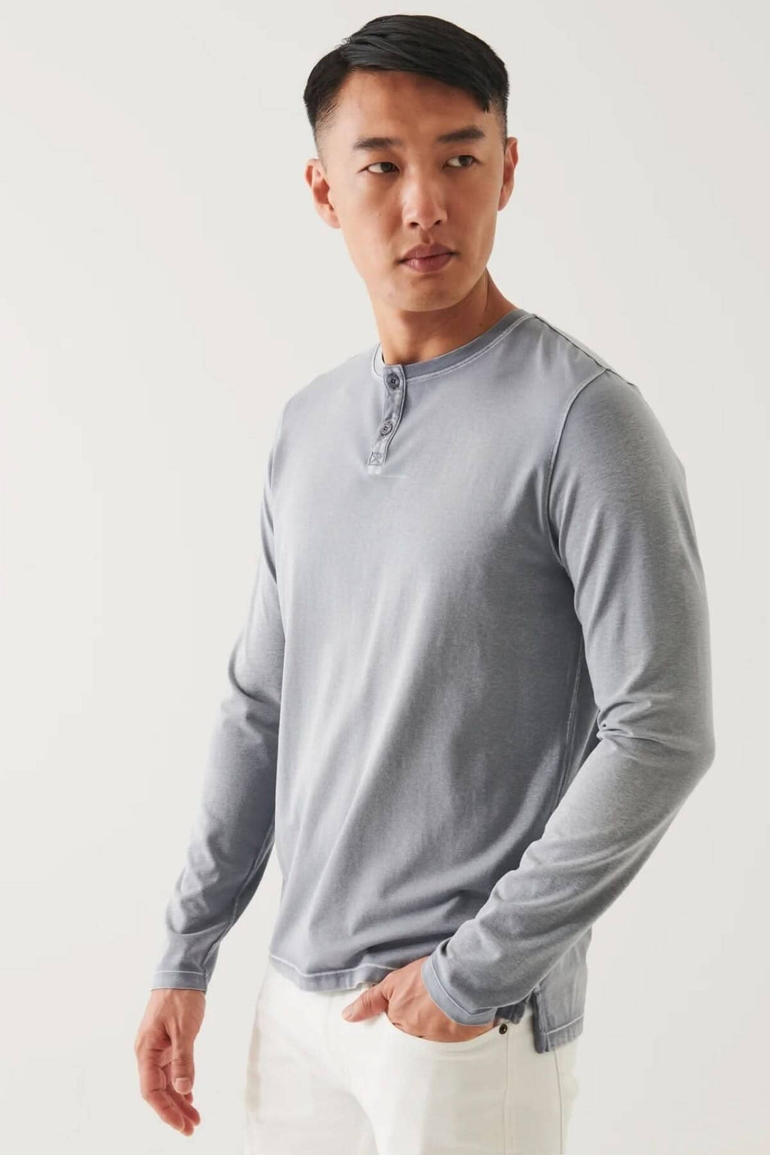Homme portant un henley en coton stretch gris, à manches longues, style vintage, sur fond clair.