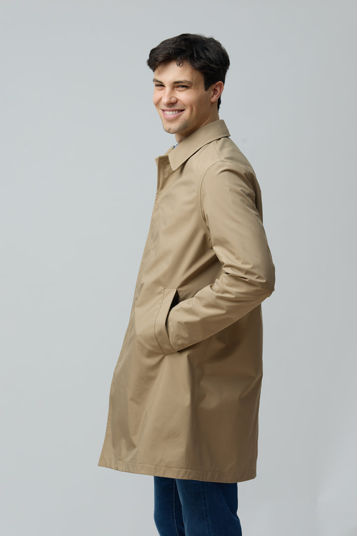 Homme portant un imperméable en microfibre technique au fini ultra-mat, coupe classique, couleur beige.