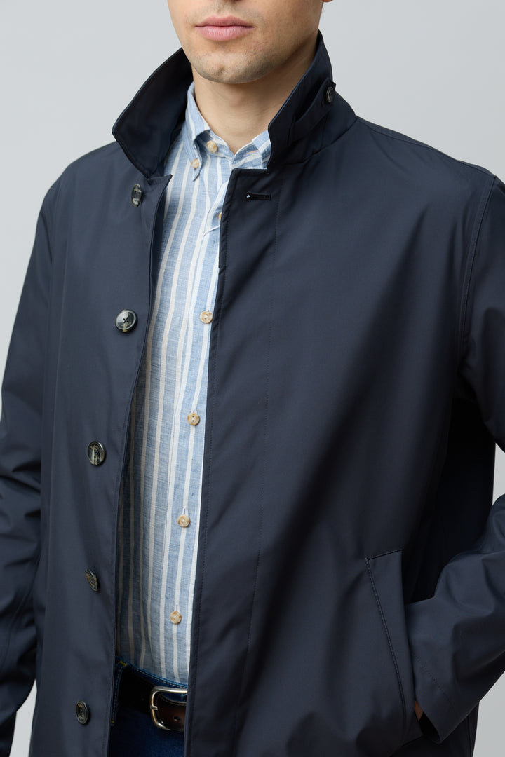 Homme portant un imperméable en microfibre technique, finition ultra-mat.
