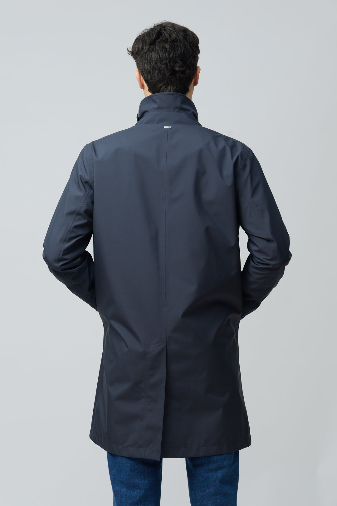 Homme portant un imperméable en microfibre technique au fini ultra-mat et coupe classique, vu de dos, avec col chemise et manches longues.