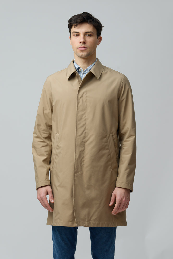 Homme portant un imperméable en microfibre technique, coupe classique, couleur beige, avec col chemise, idéal pour mi-saison.