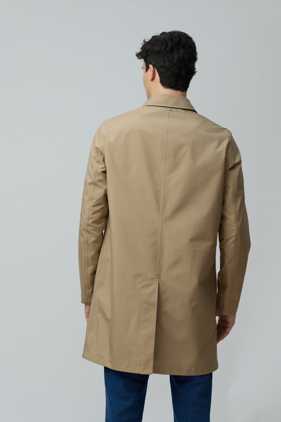 Homme portant un imperméable en microfibre technique, coupe classique, finition ultra-mat, idéal pour mi-saison en ville.