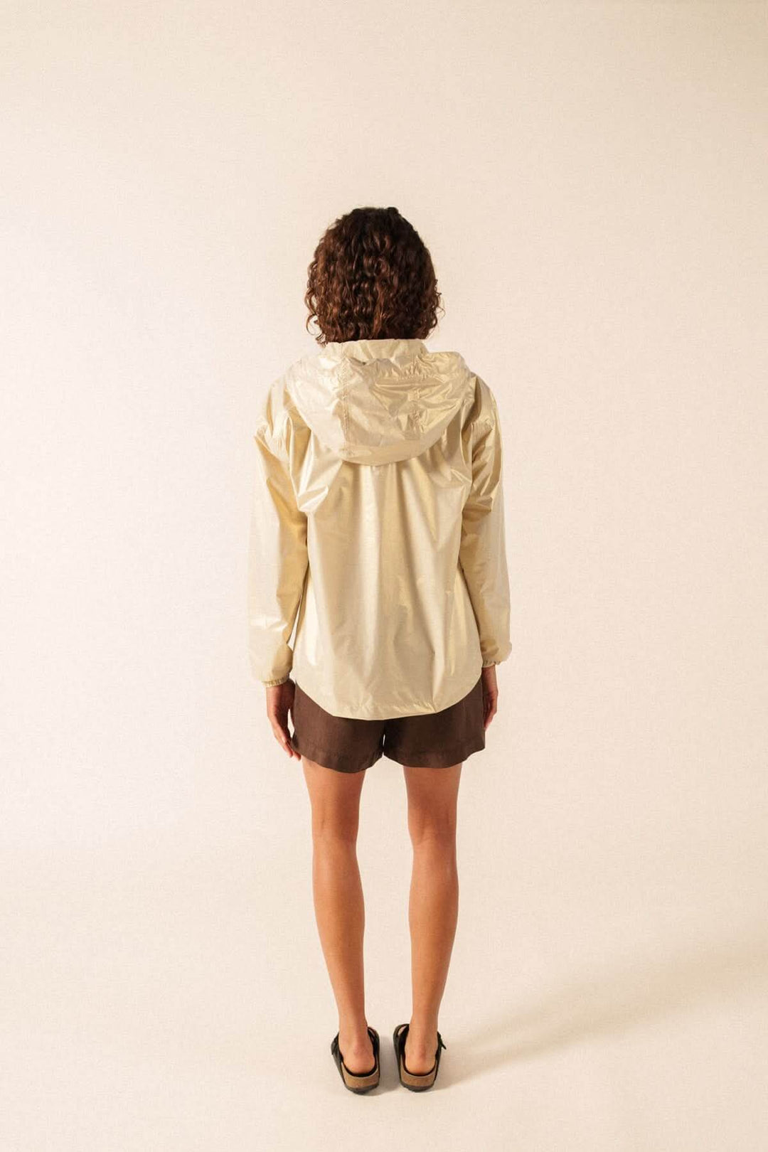 Vue arrière d'une personne portant l'imperméable léger à capuche STE IRIS beige, adapté pour un style urbain ou décontracté.