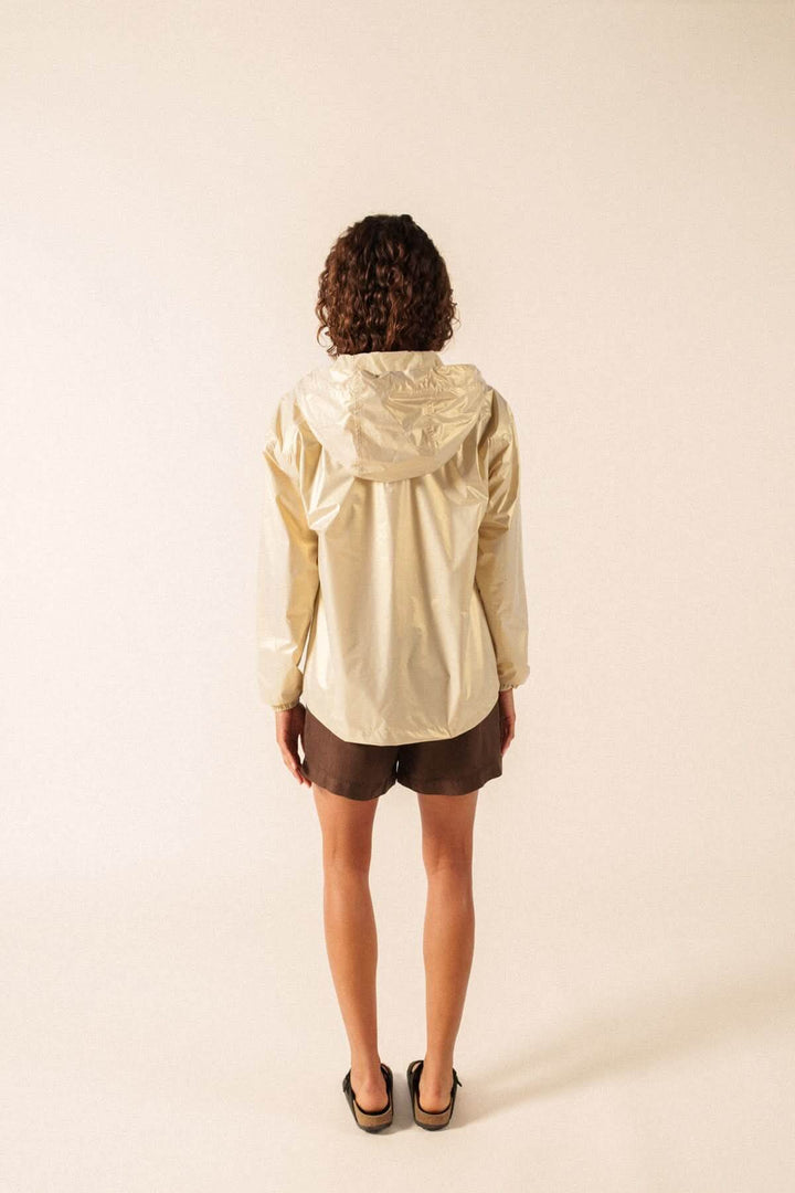Vue arrière d'une personne portant l'imperméable léger à capuche STE IRIS beige, adapté pour un style urbain ou décontracté.