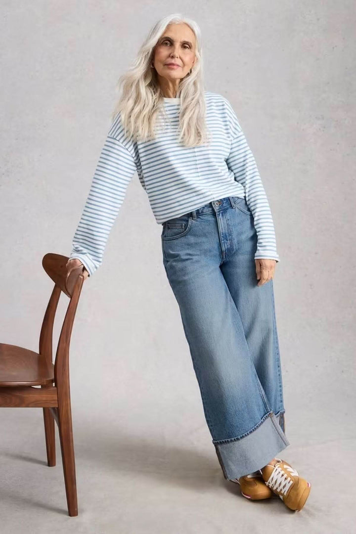 Femme portant un Jean Bailey Straight à revers avec un ourlet large retroussé, tenant une chaise, en tenue décontractée.