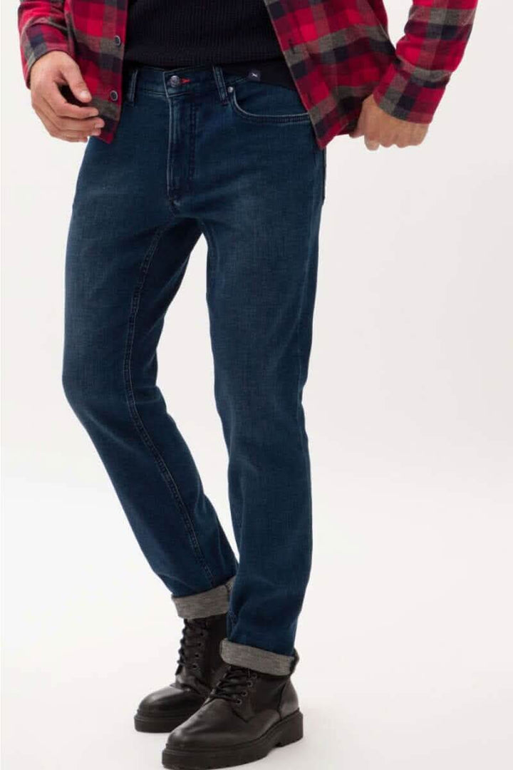 Jean Chuck en denim bleu avec coupe décontractée, porté avec une chemise à carreaux et des bottes noires.