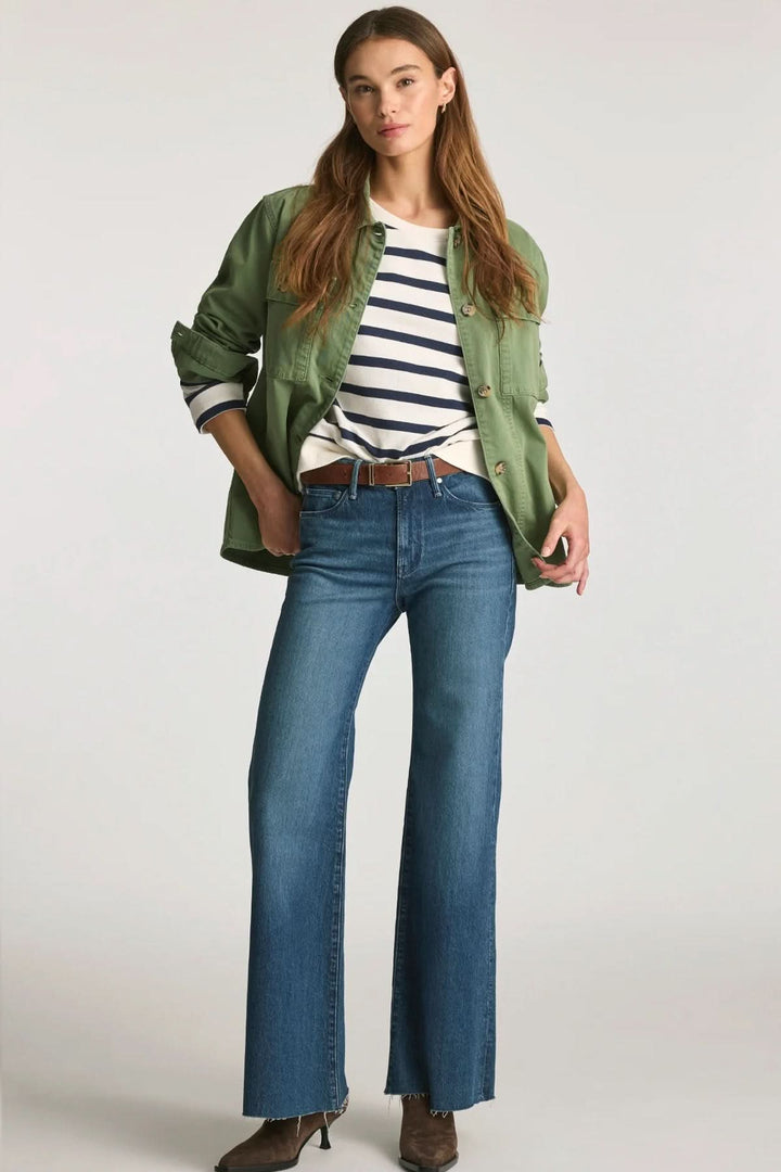Jean Grace jambe large taille mi-haute avec une femme portant un jean bleu, un manteau vert et un haut rayé.