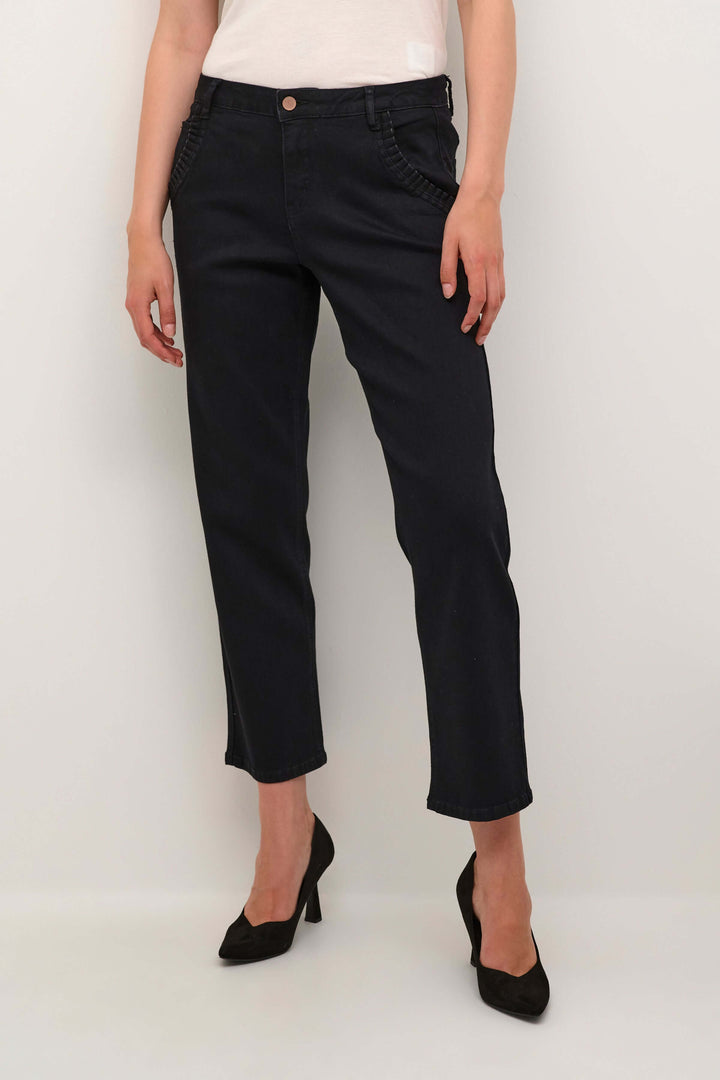 Jean Raja à jambe droite, taille mi-haute, poches obliques, porté avec des talons, style moderne et élégant.