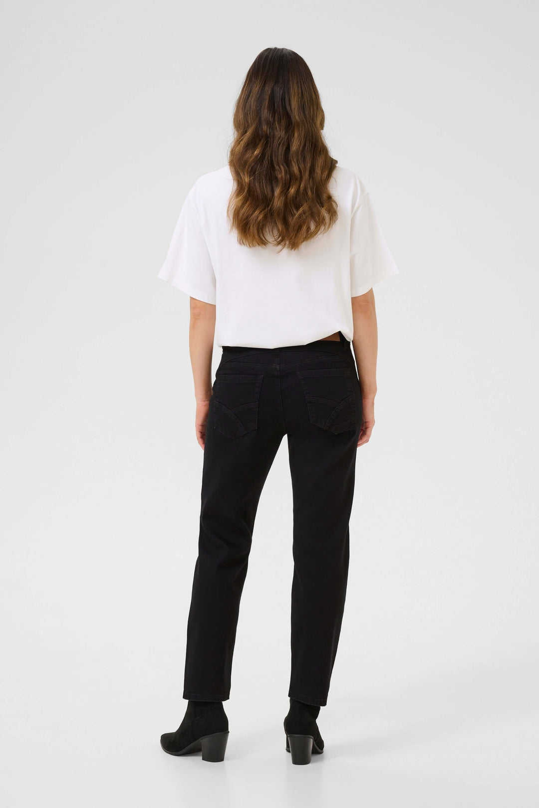 Femme de dos portant un jean droit noir avec t-shirt blanc, vue moderne et élégante.